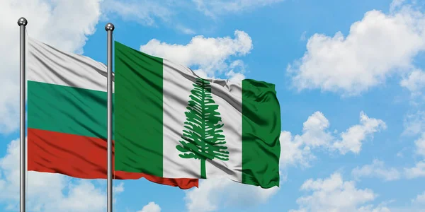 Bandera de Bulgaria y Norfolk Island ondeando en el viento contra el cielo azul nublado blanco juntos. Concepto diplomático, relaciones internacionales . — Foto de Stock