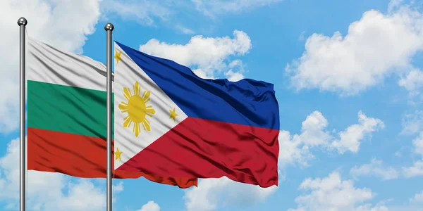 Bandera de Bulgaria y Filipinas ondeando en el viento contra el cielo azul nublado blanco juntos. Concepto diplomático, relaciones internacionales . — Foto de Stock