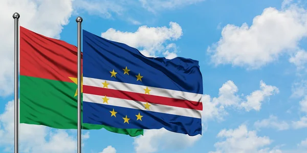 Burkina Faso y la bandera de Cabo Verde ondeando en el viento contra el cielo azul nublado blanco juntos. Concepto diplomático, relaciones internacionales . — Foto de Stock