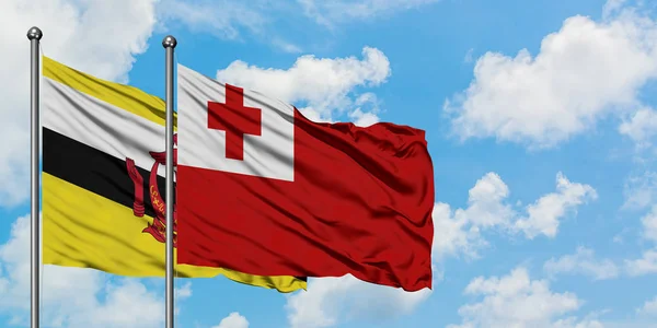 Brunei and Tonga flag waving in the wind against white cloudy blue sky together. Diplomacy concept, international relations.