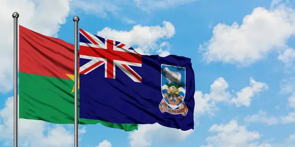 Bandera de Burkina Faso y las Islas Malvinas ondeando en el viento contra el cielo azul nublado blanco juntos. Concepto diplomático, relaciones internacionales . — Foto de Stock