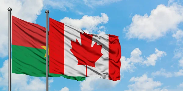 Burkina Faso y la bandera de Canadá ondeando en el viento contra el cielo azul nublado blanco juntos. Concepto diplomático, relaciones internacionales . — Foto de Stock