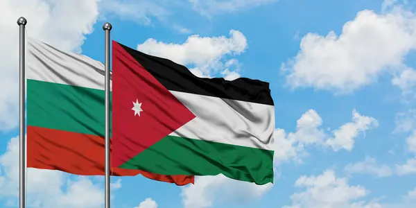 Bandera de Bulgaria y Jordania ondeando en el viento contra el cielo azul nublado blanco juntos. Concepto diplomático, relaciones internacionales . — Foto de Stock