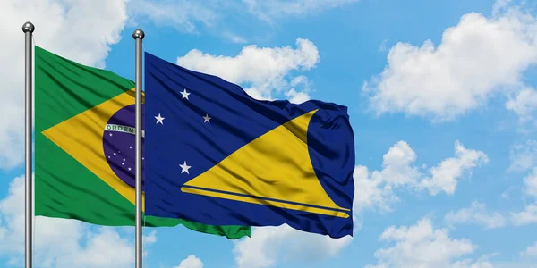 Bandeira do Brasil e Tokelau agitando no vento contra o céu azul nublado branco juntos. Conceito de diplomacia, relações internacionais . — Fotografia de Stock