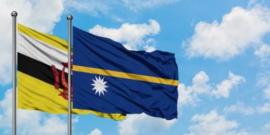 Brunei ve Nauru bayrağı birlikte beyaz bulutlu mavi gökyüzüne karşı rüzgarda sallayarak. Diplomasi kavramı, uluslararası ilişkiler.