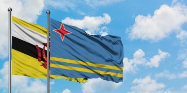 Brunei ve Aruba bayrağı birlikte beyaz bulutlu mavi gökyüzüne karşı rüzgarda sallayarak. Diplomasi kavramı, uluslararası ilişkiler.
