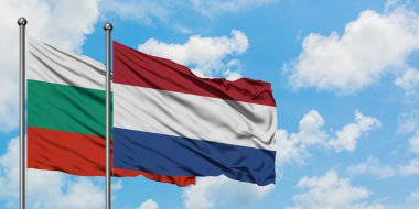 Bulgaristan ve Hollanda bayrağı birlikte beyaz bulutlu mavi gökyüzüne karşı rüzgarsal sallayarak. Diplomasi kavramı, uluslararası ilişkiler.