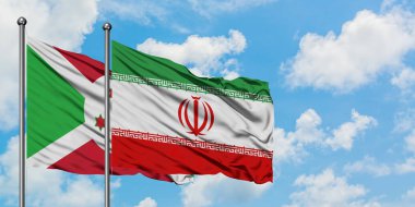 Burundi ve İran bayrağı birlikte beyaz bulutlu mavi gökyüzüne karşı rüzgarda sallayarak. Diplomasi kavramı, uluslararası ilişkiler.