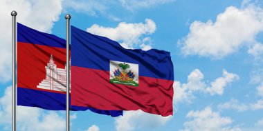 Kamboçya ve Haiti bayrağı birlikte beyaz bulutlu mavi gökyüzüne karşı rüzgarda sallayarak. Diplomasi kavramı, uluslararası ilişkiler.