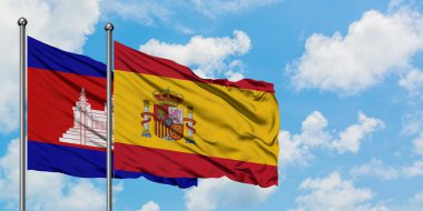 Kamboçya ve İspanya bayrağı birlikte beyaz bulutlu mavi gökyüzüne karşı rüzgarsal sallayarak. Diplomasi kavramı, uluslararası ilişkiler.