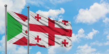 Burundi ve Gürcistan bayrağı birlikte beyaz bulutlu mavi gökyüzüne karşı rüzgarda sallayarak. Diplomasi kavramı, uluslararası ilişkiler.