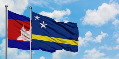 Kamboçya ve Curacao bayrağı birlikte beyaz bulutlu mavi gökyüzüne karşı rüzgarda sallayarak. Diplomasi kavramı, uluslararası ilişkiler.