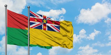 Burkina Faso ve Niue bayrağı birlikte beyaz bulutlu mavi gökyüzüne karşı rüzgarda sallayarak. Diplomasi kavramı, uluslararası ilişkiler.