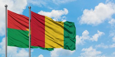 Burkina Faso ve Gine bayrağı birlikte beyaz bulutlu mavi gökyüzüne karşı rüzgarda sallayarak. Diplomasi kavramı, uluslararası ilişkiler.
