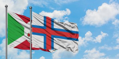 Burundi ve Faroe Adaları bayrağı birlikte beyaz bulutlu mavi gökyüzüne karşı rüzgarda sallayarak. Diplomasi kavramı, uluslararası ilişkiler.