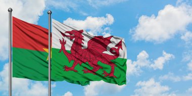 Burkina Faso ve Galler bayrağı birlikte beyaz bulutlu mavi gökyüzüne karşı rüzgarda sallayarak. Diplomasi kavramı, uluslararası ilişkiler.