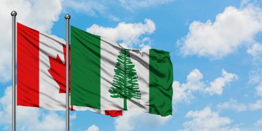 Kanada ve Norfolk Adası bayrağı birlikte beyaz bulutlu mavi gökyüzüne karşı rüzgarda sallayarak. Diplomasi kavramı, uluslararası ilişkiler.