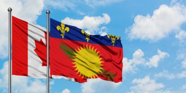 Kanada ve Guadeloupe bayrağı birlikte beyaz bulutlu mavi gökyüzüne karşı rüzgarda sallayarak. Diplomasi kavramı, uluslararası ilişkiler.