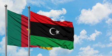 Kamerun ve Libya bayrağı birlikte beyaz bulutlu mavi gökyüzüne karşı rüzgarsal sallayarak. Diplomasi kavramı, uluslararası ilişkiler.