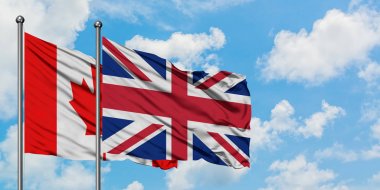 Kanada ve Birleşik Krallık bayrağı birlikte beyaz bulutlu mavi gökyüzüne karşı rüzgarda sallayarak. Diplomasi kavramı, uluslararası ilişkiler.