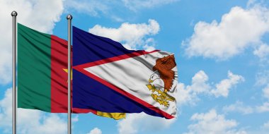 Kamerun ve Amerikan Samoası bayrağı birlikte beyaz bulutlu mavi gökyüzüne karşı rüzgarda sallayarak. Diplomasi kavramı, uluslararası ilişkiler.