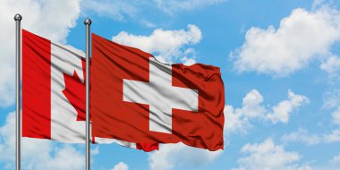 Kanada ve İsviçre bayrağı birlikte beyaz bulutlu mavi gökyüzüne karşı rüzgarsal sallayarak. Diplomasi kavramı, uluslararası ilişkiler.