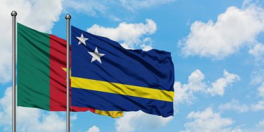 Kamerun ve Curacao bayrağı birlikte beyaz bulutlu mavi gökyüzüne karşı rüzgarda sallayarak. Diplomasi kavramı, uluslararası ilişkiler.