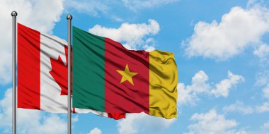 Kanada ve Kamerun bayrağı birlikte beyaz bulutlu mavi gökyüzüne karşı rüzgarda sallayarak. Diplomasi kavramı, uluslararası ilişkiler.