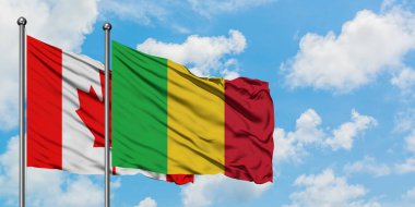 Kanada ve Mali bayrağı birlikte beyaz bulutlu mavi gökyüzüne karşı rüzgarda sallayarak. Diplomasi kavramı, uluslararası ilişkiler.