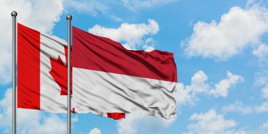 Kanada ve Endonezya bayrağı birlikte beyaz bulutlu mavi gökyüzüne karşı rüzgarsal sallayarak. Diplomasi kavramı, uluslararası ilişkiler.