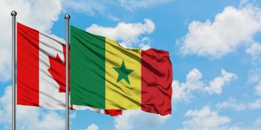 Kanada ve Senegal bayrağı birlikte beyaz bulutlu mavi gökyüzüne karşı rüzgarda sallayarak. Diplomasi kavramı, uluslararası ilişkiler.