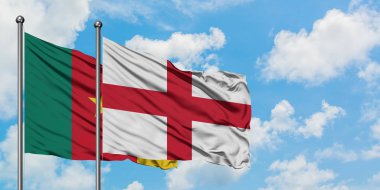 Kamerun ve İngiltere bayrağı birlikte beyaz bulutlu mavi gökyüzüne karşı rüzgarda sallayarak. Diplomasi kavramı, uluslararası ilişkiler.