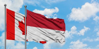 Kanada ve Monako bayrağı birlikte beyaz bulutlu mavi gökyüzüne karşı rüzgarda sallayarak. Diplomasi kavramı, uluslararası ilişkiler.