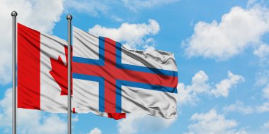 Kanada ve Faroe Adaları bayrağı birlikte beyaz bulutlu mavi gökyüzüne karşı rüzgarda sallayarak. Diplomasi kavramı, uluslararası ilişkiler.