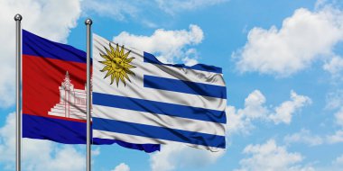 Kamboçya ve Uruguay bayrağı birlikte beyaz bulutlu mavi gökyüzüne karşı rüzgarsal sallayarak. Diplomasi kavramı, uluslararası ilişkiler.
