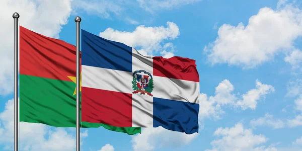 ブルキナファソとドミニカ共和国の旗は、一緒に白い曇り青い空に対して風に手を振ります。外交概念、国際関係. — ストック写真