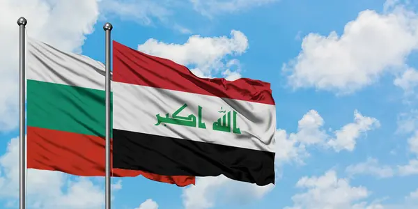 Bandera de Bulgaria e Irak ondeando en el viento contra el cielo azul nublado blanco juntos. Concepto diplomático, relaciones internacionales . — Foto de Stock