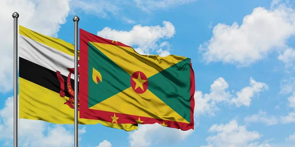 Brunei und Grenada-Flagge wehen gemeinsam im Wind gegen den wolkenverhangenen blauen Himmel. Diplomatie-Konzept, internationale Beziehungen. — Stockfoto