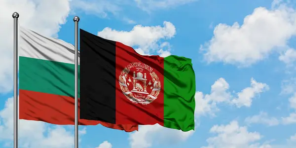 Bandera de Bulgaria y Afganistán ondeando en el viento contra el cielo azul nublado blanco juntos. Concepto diplomático, relaciones internacionales . — Foto de Stock