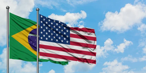 Brazil and United States flag waving in the wind against white cloudy blue sky together. Diplomacy concept, international relations. — Stock Photo, Image