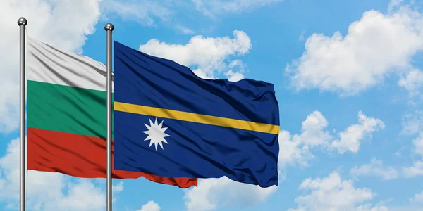 Bandera de Bulgaria y Nauru ondeando en el viento contra el cielo azul nublado blanco juntos. Concepto diplomático, relaciones internacionales . — Foto de Stock