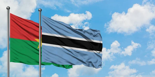 Burkina Faso e Botswana sventolano nel vento contro il bianco cielo azzurro nuvoloso insieme. Concetto di diplomazia, relazioni internazionali . — Foto Stock