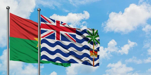 Burkina Faso ve İngiliz Hint Okyanusu Toprakları bayrağı birlikte beyaz bulutlu mavi gökyüzüne karşı rüzgarda sallayarak. Diplomasi kavramı, uluslararası ilişkiler.