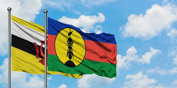 Brunei and New Caledonia flag waving in the wind against white cloudy blue sky together. Diplomacy concept, international relations. — Stock Photo, Image