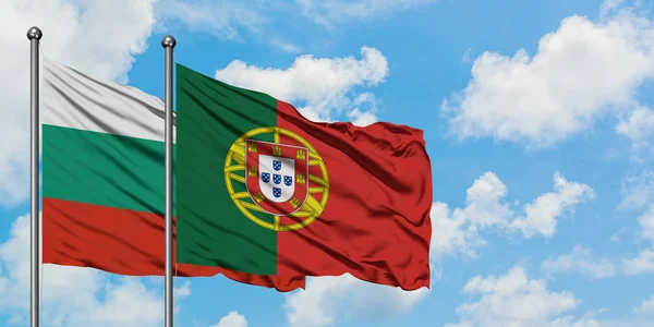 A bandeira da Bulgária e de Portugal agitando no vento contra o céu azul nublado branco juntos. Conceito de diplomacia, relações internacionais . — Fotografia de Stock
