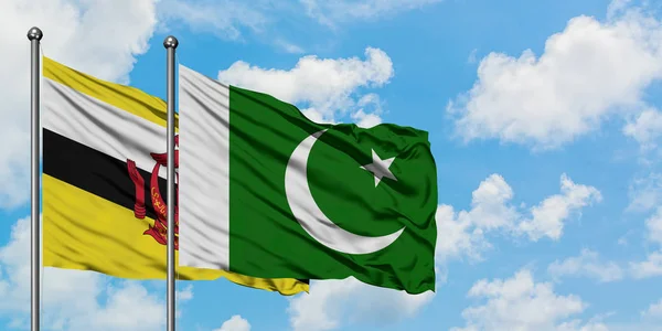 Bandera de Brunei y Pakistán ondeando en el viento contra el cielo azul nublado blanco juntos. Concepto diplomático, relaciones internacionales . — Foto de Stock