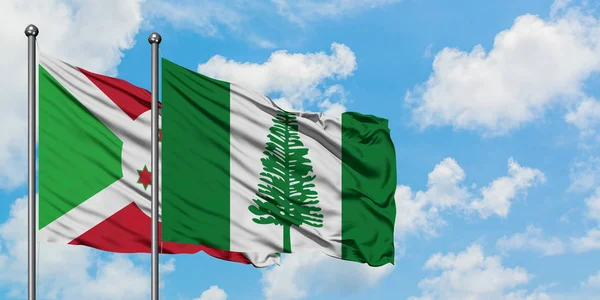 Burundi en Norfolk Island vlag zwaaien in de wind tegen witte bewolkte blauwe hemel samen. Diplomatie concept, internationale betrekkingen. — Stockfoto
