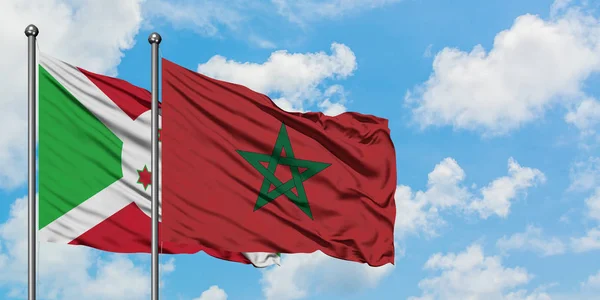 Bandera de Burundi y Marruecos ondeando en el viento contra el cielo azul nublado blanco juntos. Concepto diplomático, relaciones internacionales . — Foto de Stock