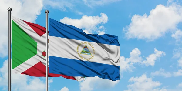 Bandera de Burundi y Nicaragua ondeando en el viento contra el cielo azul nublado blanco juntos. Concepto diplomático, relaciones internacionales . — Foto de Stock