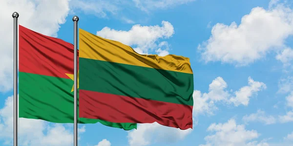 Bandera de Burkina Faso y Lituania ondeando en el viento contra el cielo azul nublado blanco juntos. Concepto diplomático, relaciones internacionales . — Foto de Stock